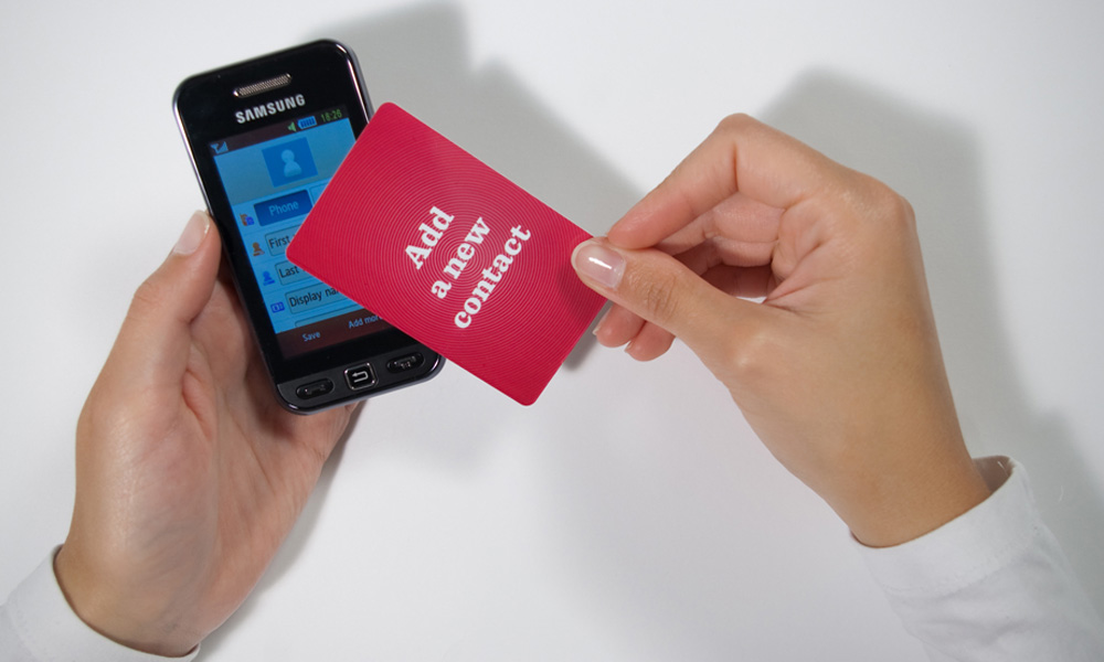 A person placing an add new contact card on top of a phone
